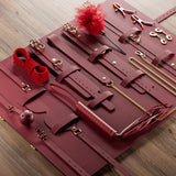 Kit BDSM Luxe 12 Pièces : pochette ouverte sur parquet, rouge